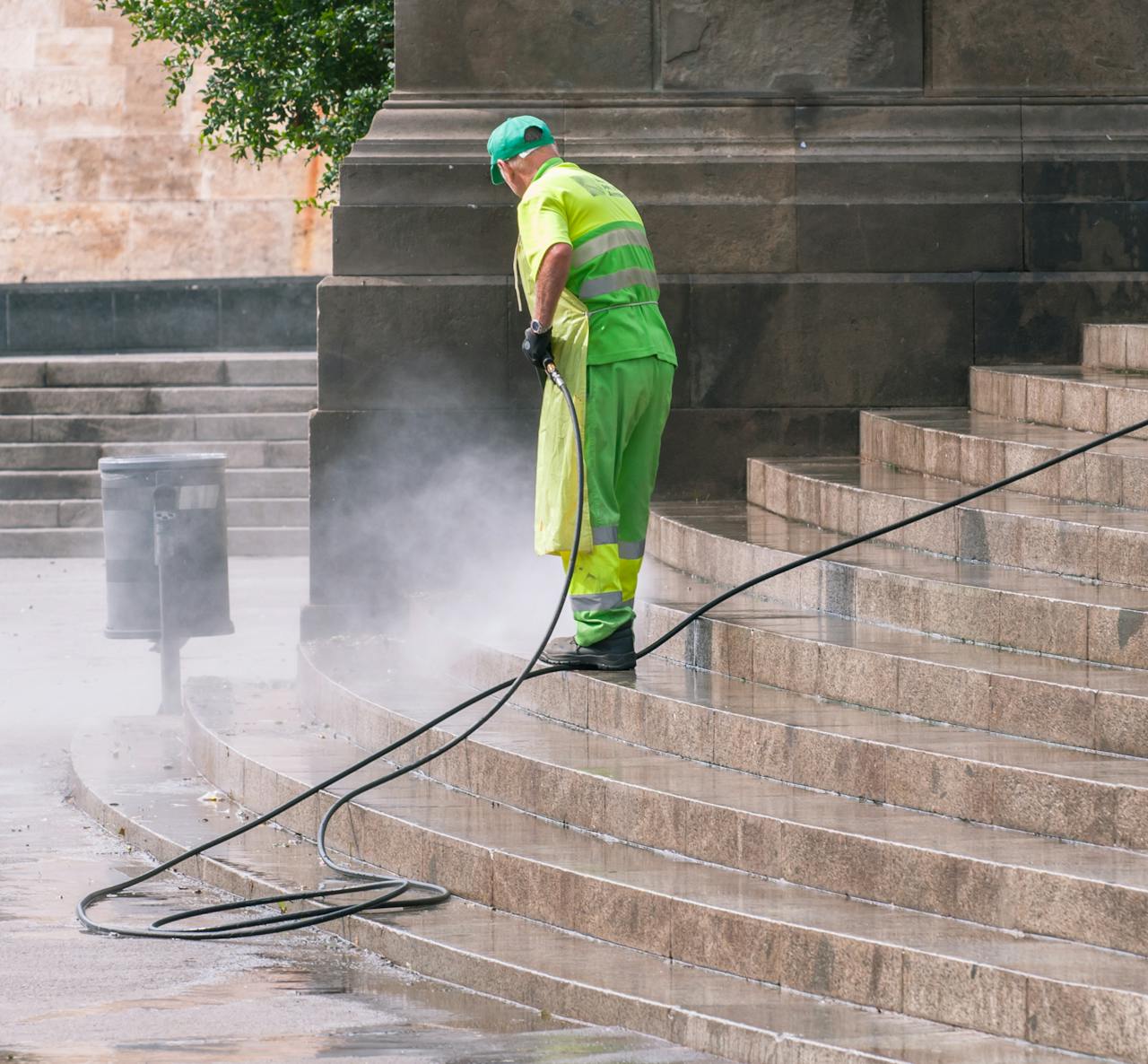 gallery-05 A street worker pressure washes stone stairs in a public park, ensuring cleanliness and safety.